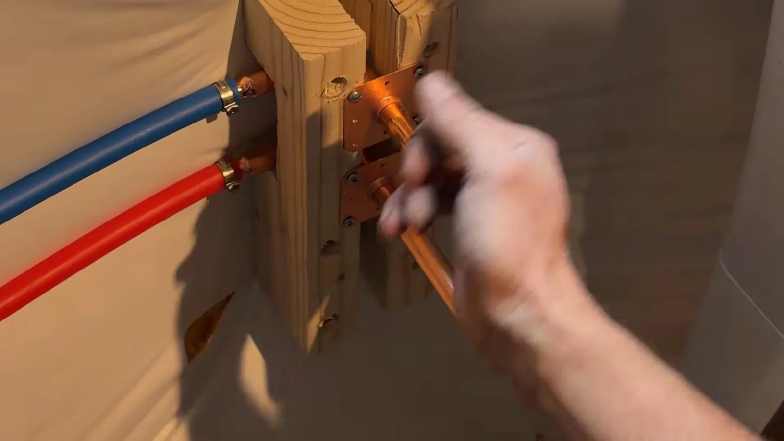 A hand steadying a copper stub on a wooden block where a blue line and a red line end.